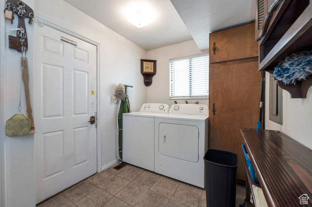 Clothes washing area featuring washer and clothes dryer and light tile patterned floors