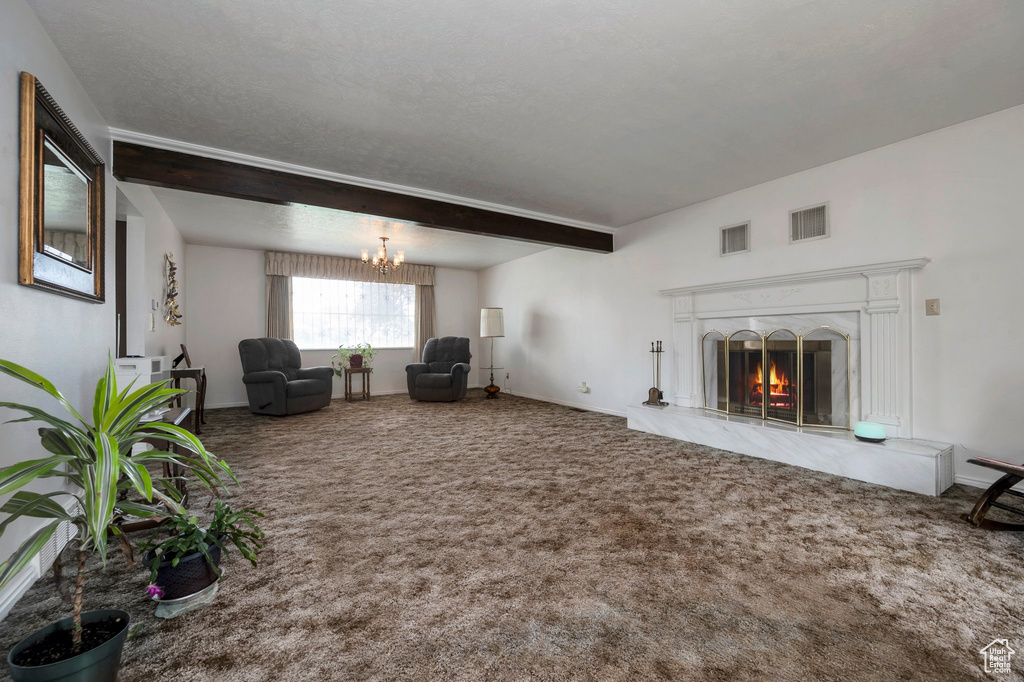 Living room with carpet floors, a chandelier, a premium fireplace, beam ceiling, and baseboards
