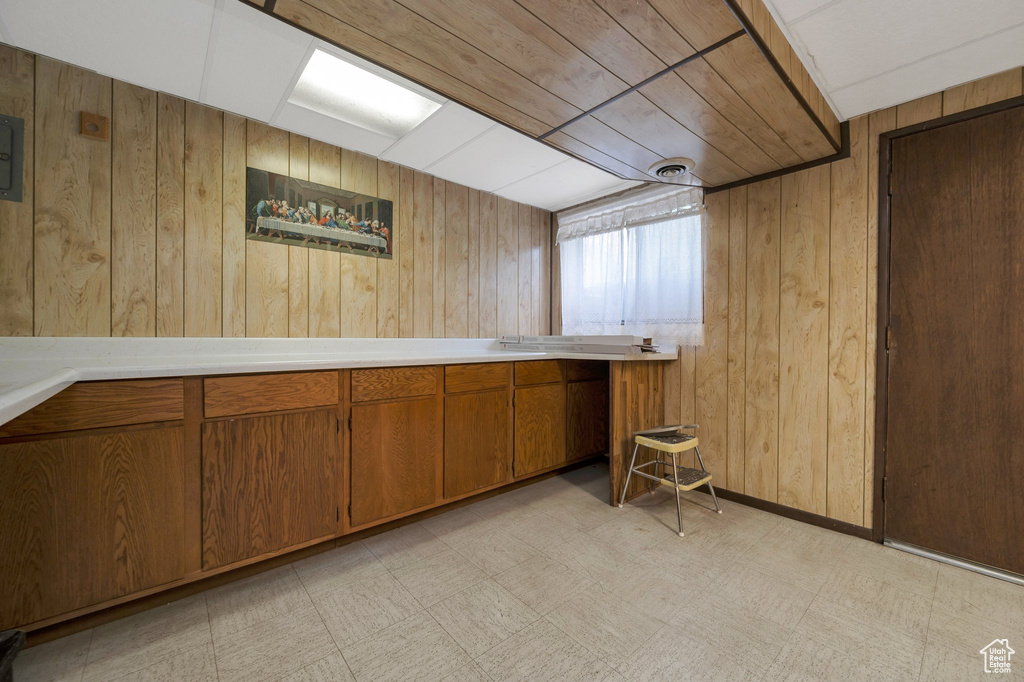 Kitchen featuring wood walls, brown cabinets, light floors, and light countertops
