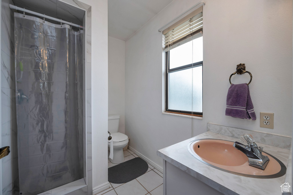 Bathroom featuring toilet, tile patterned floors, vanity, curtained shower, and baseboards