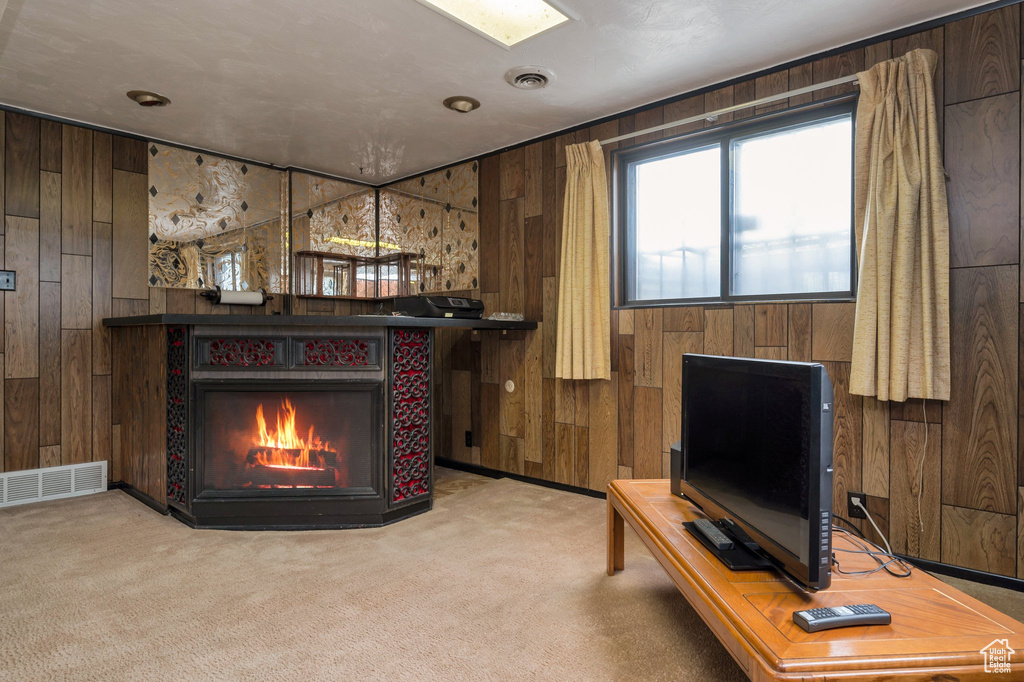 Carpeted living area with wooden walls and a warm lit fireplace