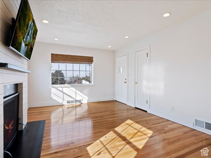 Unfurnished living room featuring light wood finished floors, visible vents, and a fireplace with flush hearth
