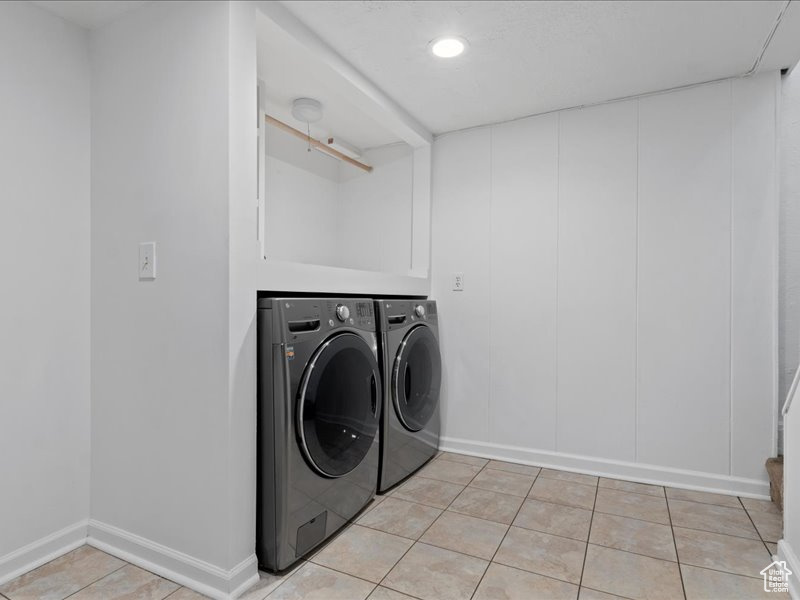 Laundry room with light tile patterned floors, independent washer and dryer, laundry area, and baseboards
