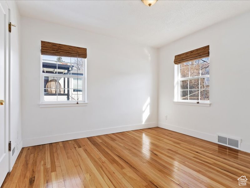 Spare room featuring visible vents, light wood finished floors, and baseboards