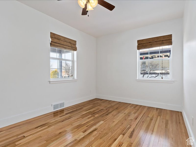 Unfurnished room featuring a ceiling fan, visible vents, baseboards, and light wood-type flooring