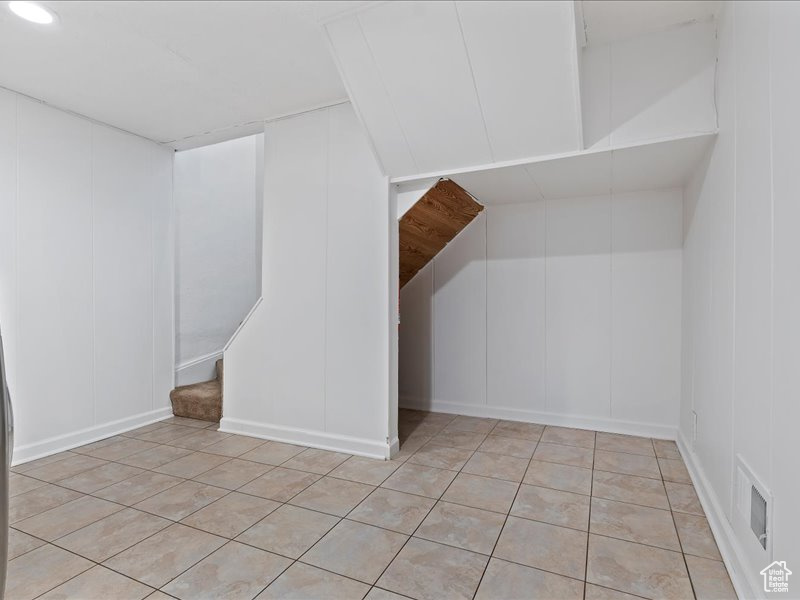 Bonus room with visible vents, light tile patterned flooring, and a decorative wall