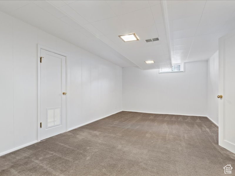 Basement with visible vents, carpet, and baseboards