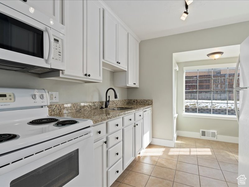 Kitchen featuring white appliances, white cabinets, a sink, baseboards, and visible vents