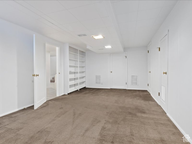 Carpeted spare room with baseboards, visible vents, and built in shelves