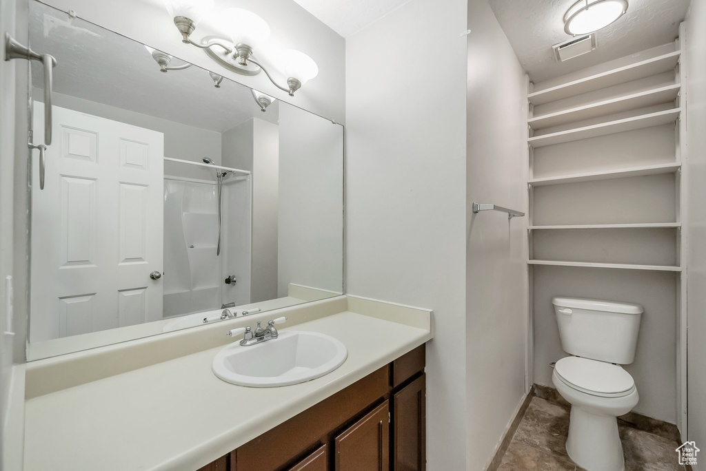 Full bath featuring baseboards, toilet, vanity, and a shower