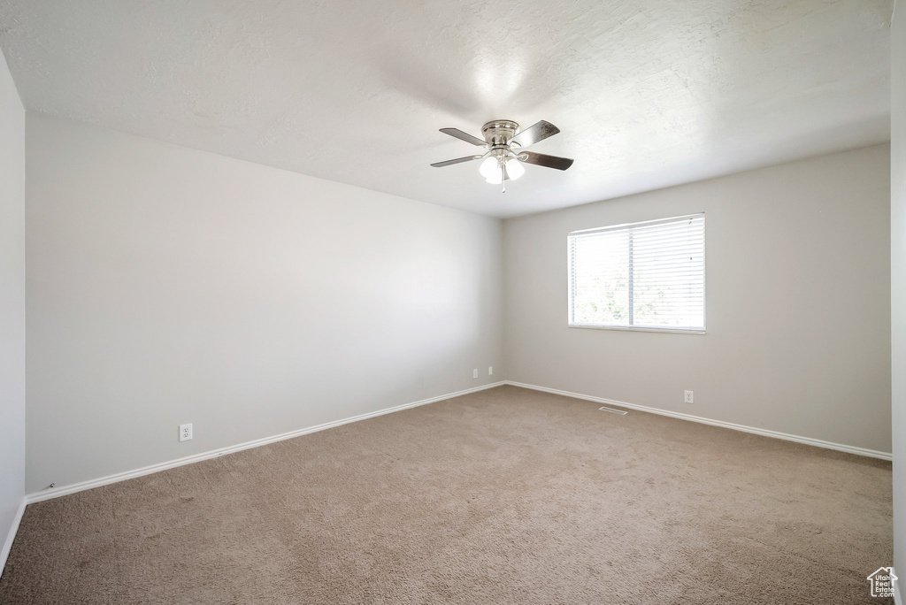 Spare room with a ceiling fan, carpet flooring, and baseboards