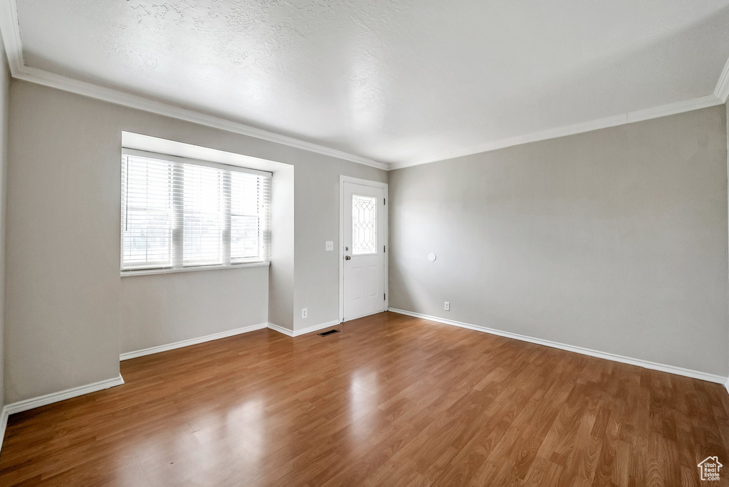 Unfurnished room featuring crown molding, wood finished floors, and baseboards