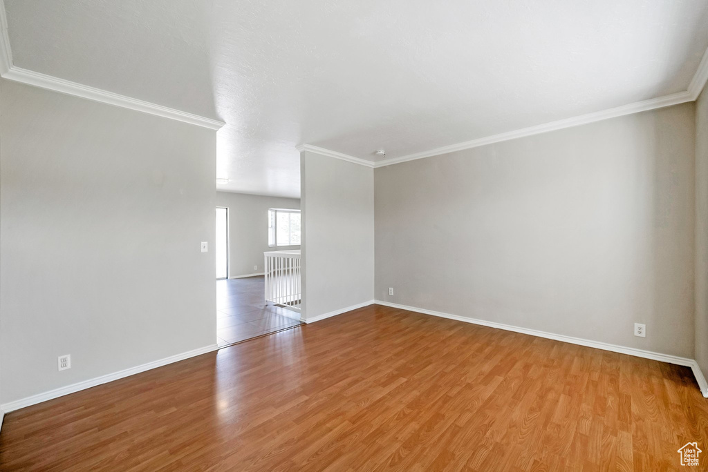 Unfurnished room featuring wood finished floors, ornamental molding, and baseboards