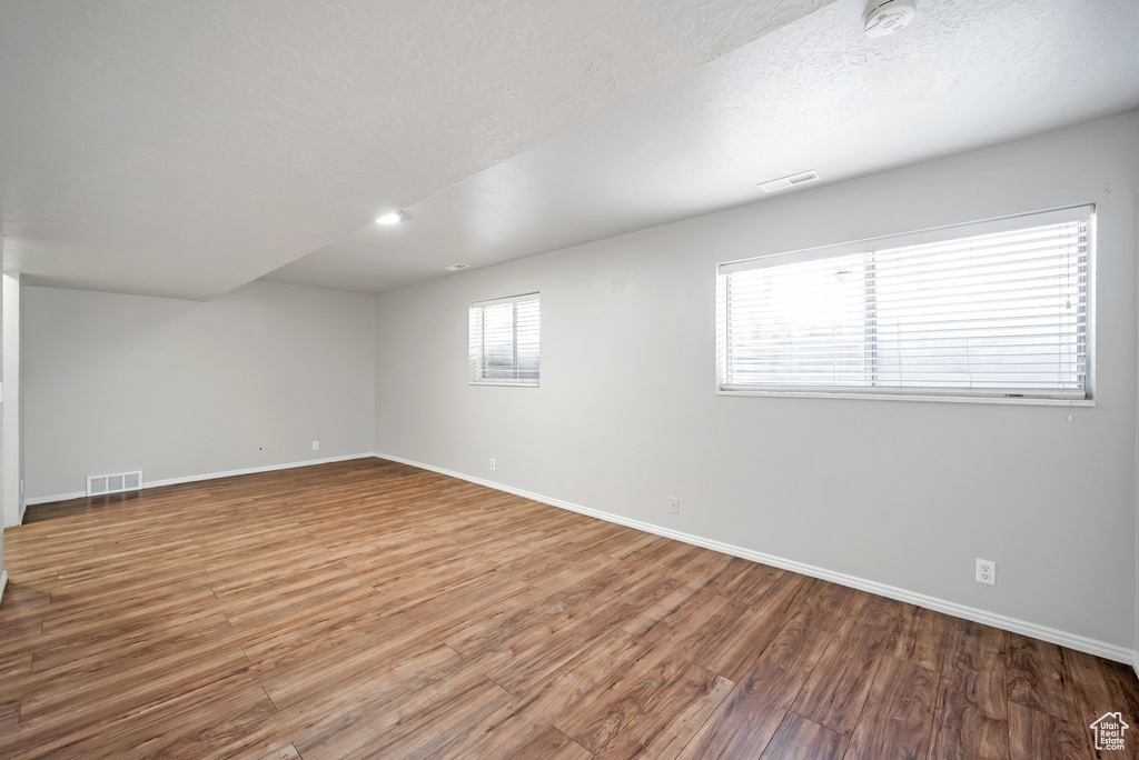 Spare room featuring a smoke detector, baseboards, wood finished floors, and a textured ceiling