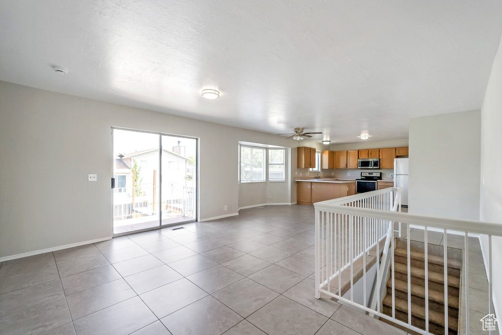 Unfurnished living room with baseboards, light tile patterned floors, and a ceiling fan
