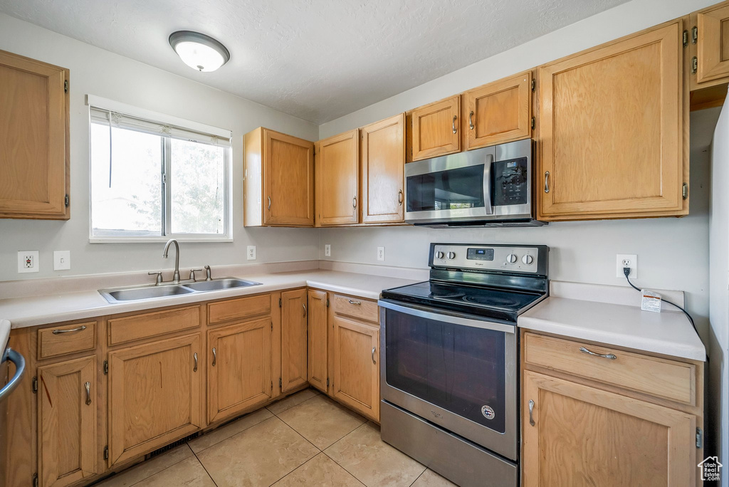 Kitchen featuring appliances with stainless steel finishes, a sink, and light countertops