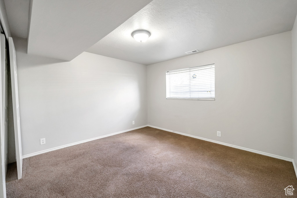 Carpeted spare room featuring baseboards