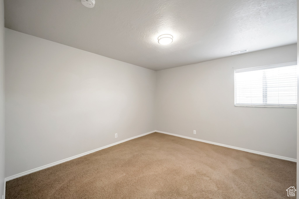 Spare room with carpet flooring, baseboards, a textured ceiling, and a smoke detector