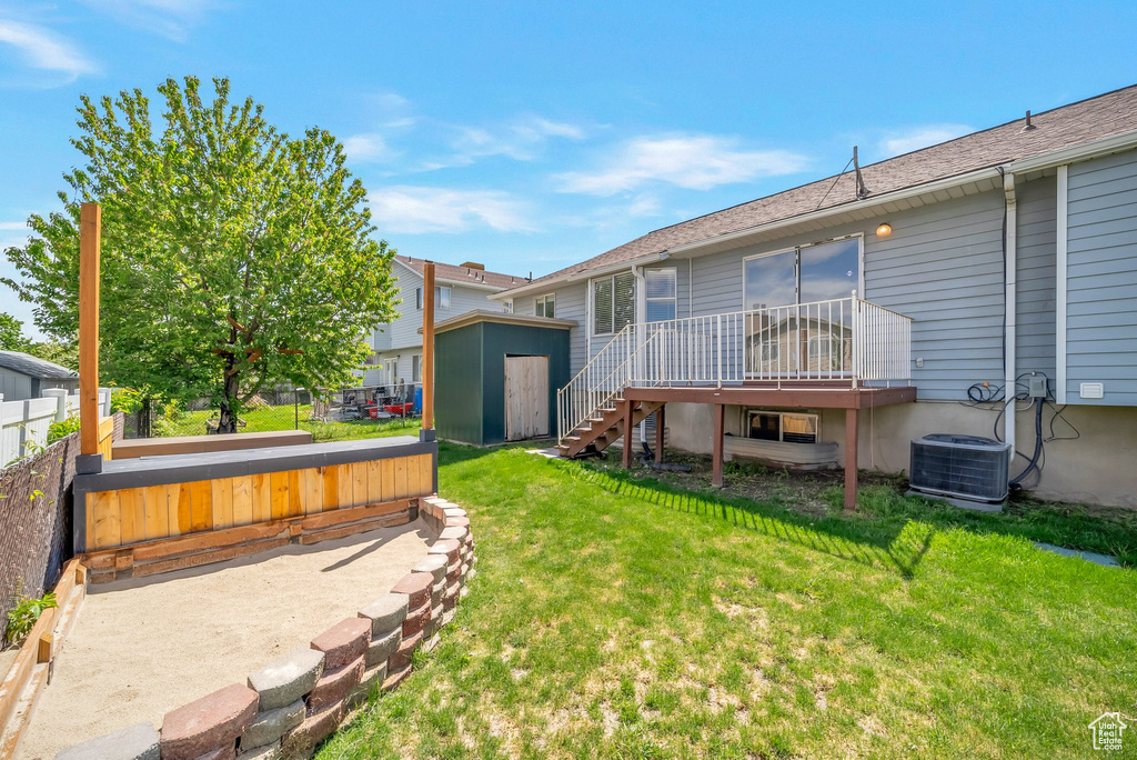 Back of house with a shed, a deck, an outdoor structure, cooling unit, and stairs