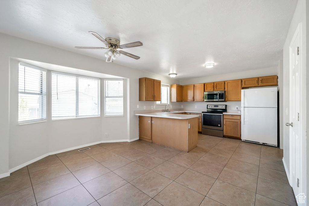Kitchen featuring appliances with stainless steel finishes, light countertops, light tile patterned flooring, and a peninsula