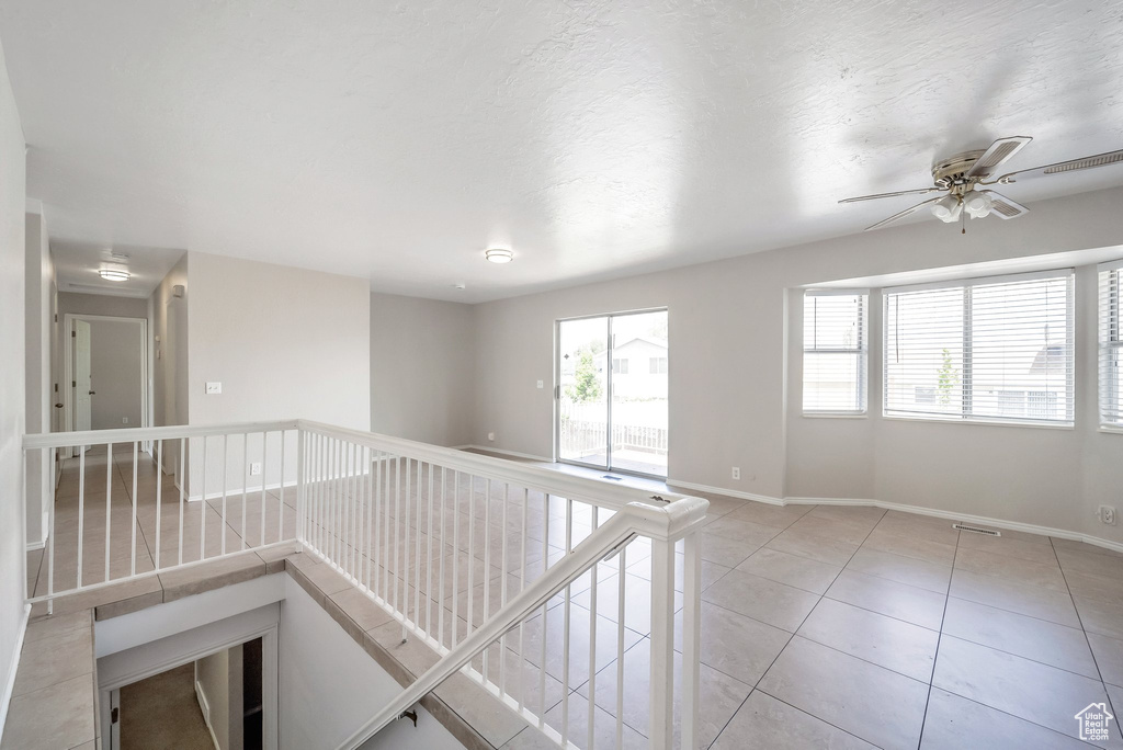 Empty room featuring baseboards, light tile patterned floors, and a ceiling fan