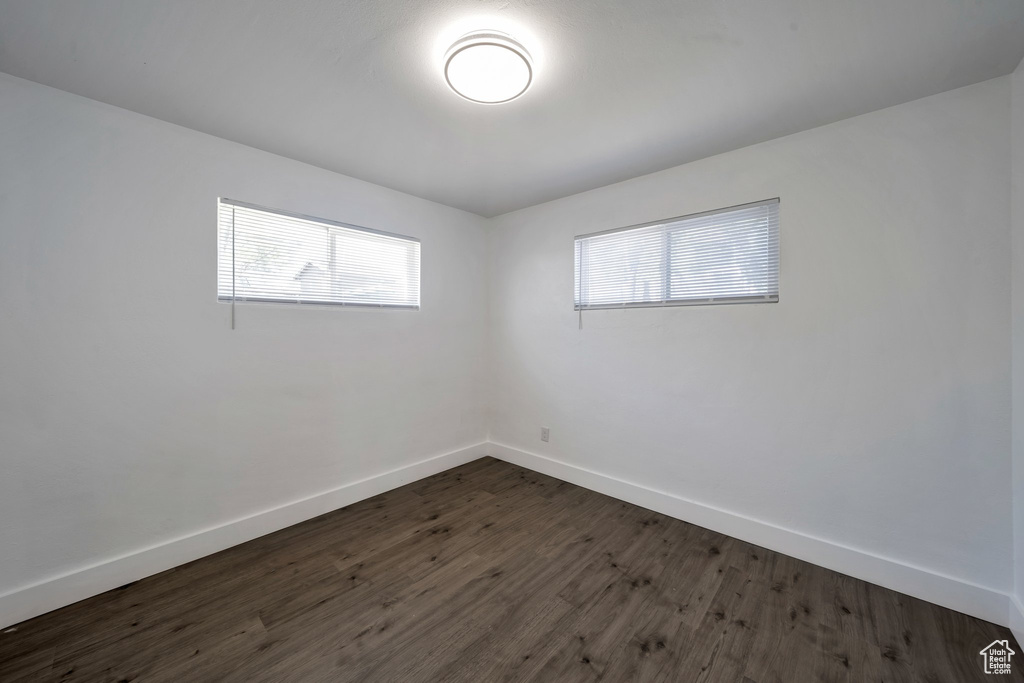 Unfurnished room with dark wood-style flooring and baseboards