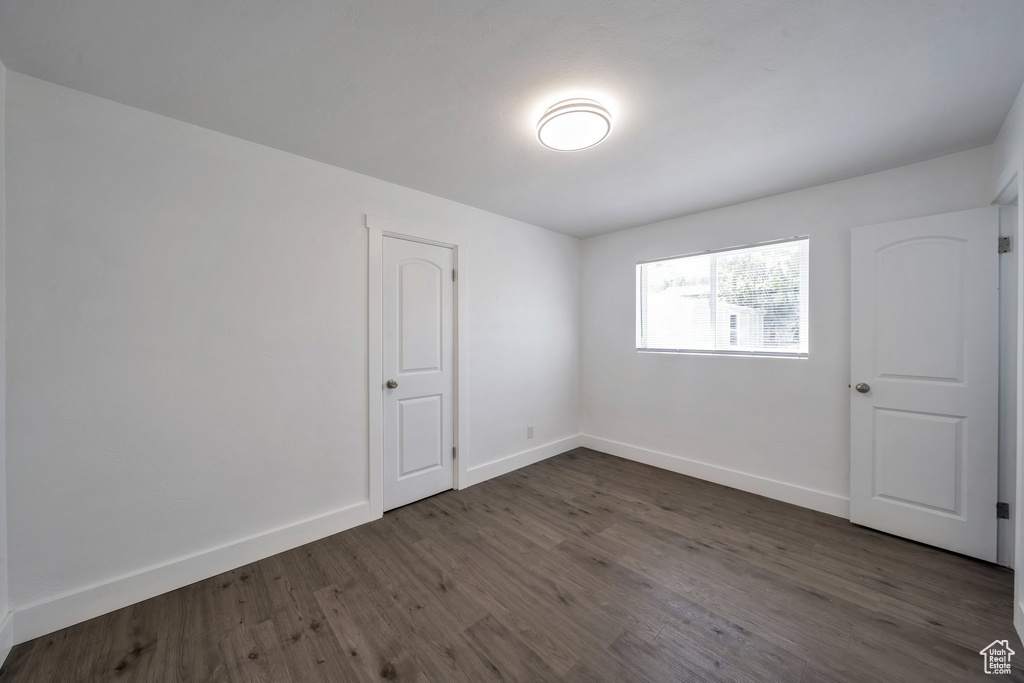 Unfurnished room featuring dark wood-style flooring and baseboards