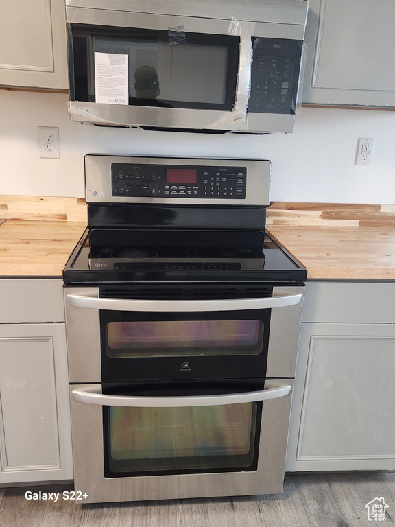 Kitchen view of appliances with stainless steel finishes, wood counters, and light wood finished floors