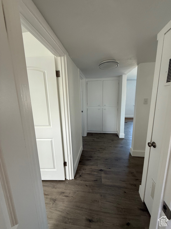 Hall featuring dark wood-type flooring and baseboards