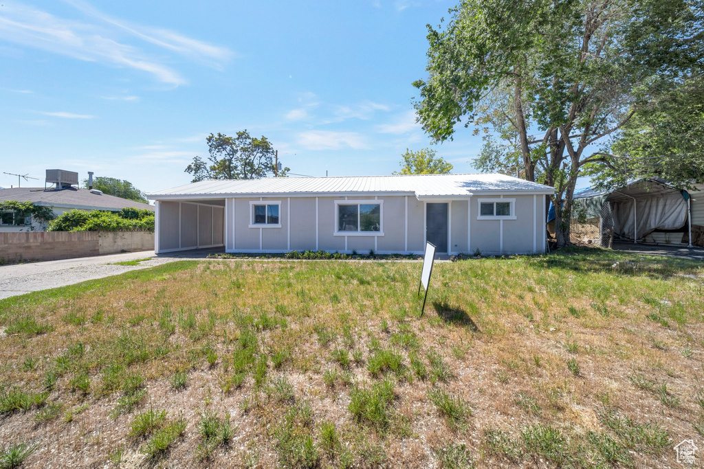 Single story home featuring a carport, a front yard, metal roof, and board and batten siding