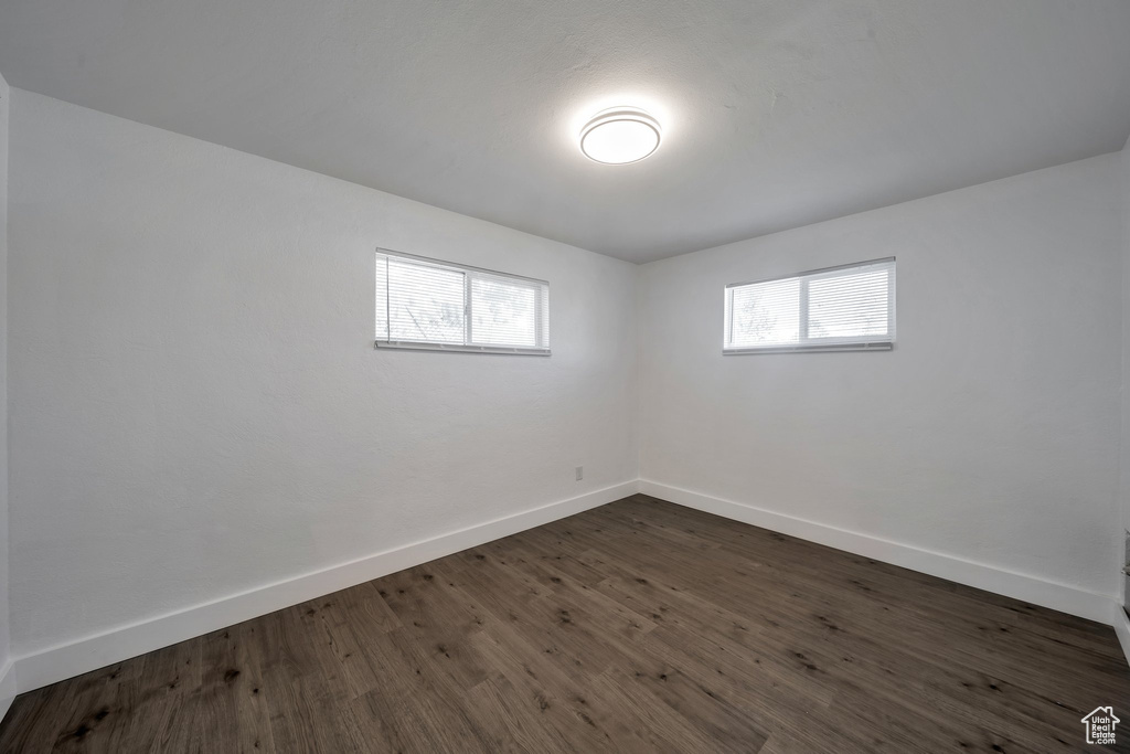 Spare room featuring plenty of natural light, baseboards, and dark wood-type flooring