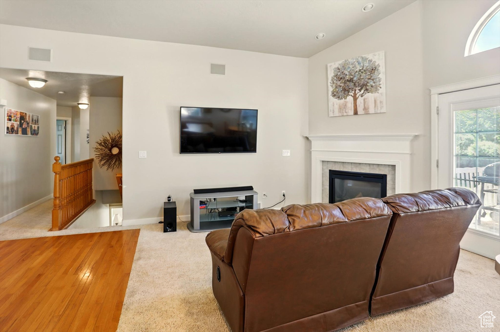Living area featuring carpet floors, a tile fireplace, baseboards, and vaulted ceiling