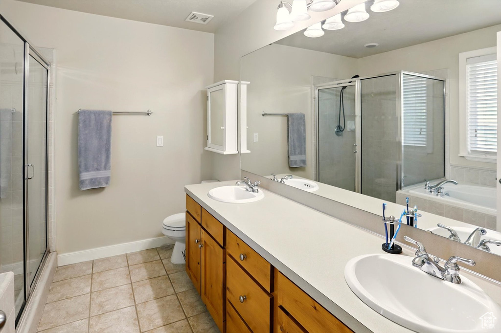 Full bathroom with a stall shower, tile patterned flooring, baseboards, toilet, and double vanity