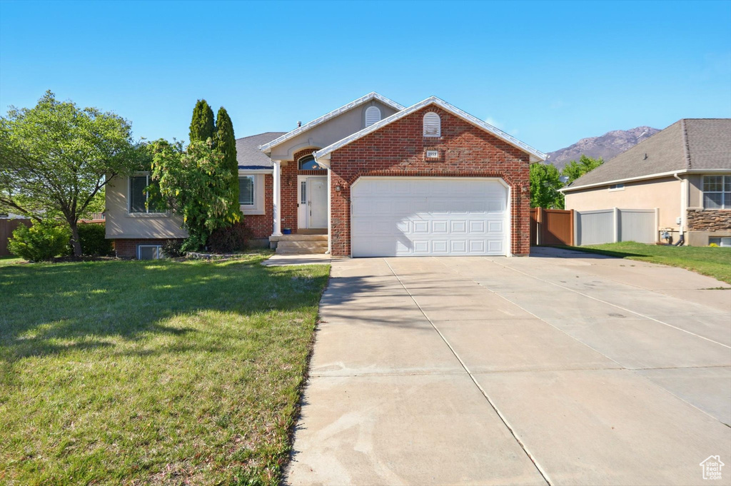 Single story home with brick siding, driveway, an attached garage, and a mountain view