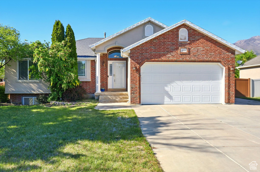 View of front of home featuring driveway, brick siding, a garage, and a front yard