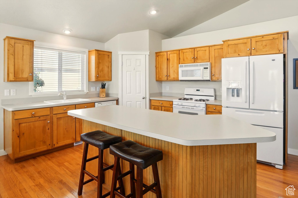 Kitchen featuring white appliances, a sink, light countertops, light wood-style floors, and lofted ceiling