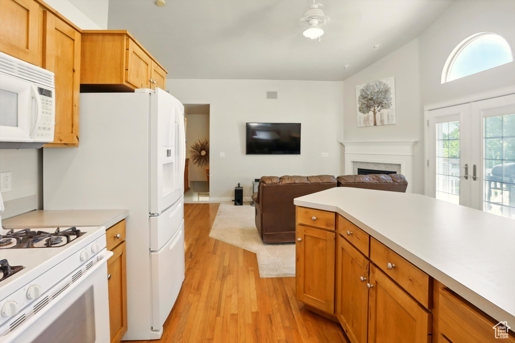 Kitchen featuring white appliances, light wood-style floors, light countertops, a fireplace, and ceiling fan
