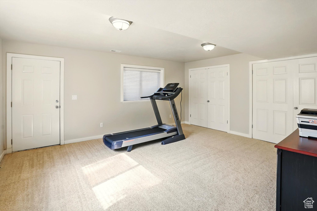 Workout area with baseboards and light colored carpet