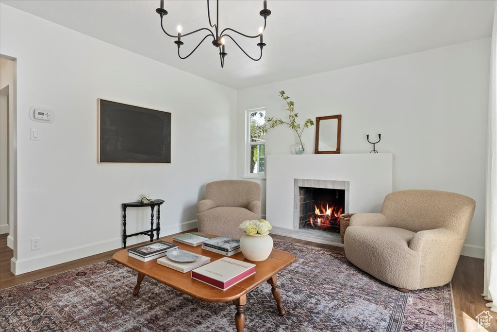 Living room with wood finished floors, baseboards, a tiled fireplace, and a chandelier