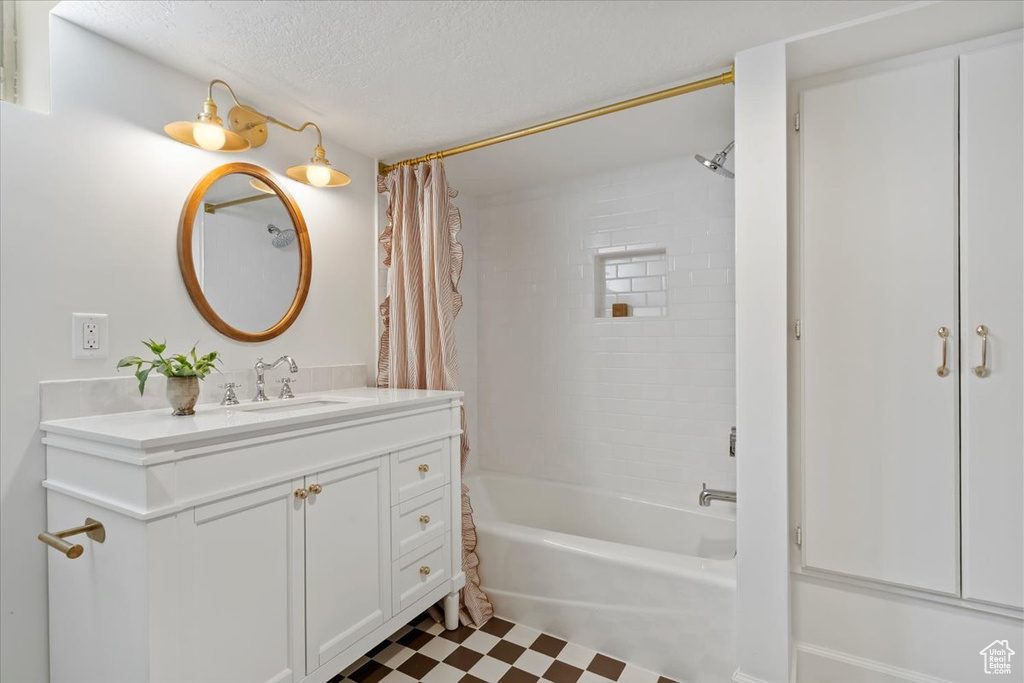 Full bath with shower / bath combo, tile patterned floors, vanity, and a textured ceiling