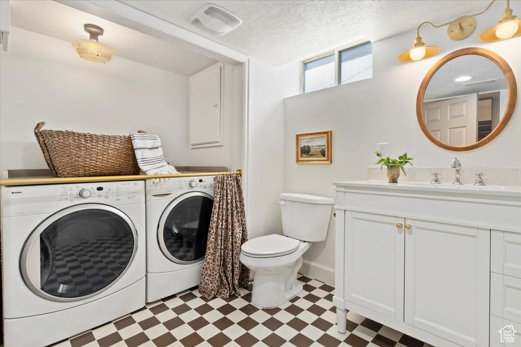 Bathroom featuring washer and clothes dryer, tile patterned floors, toilet, vanity, and baseboards