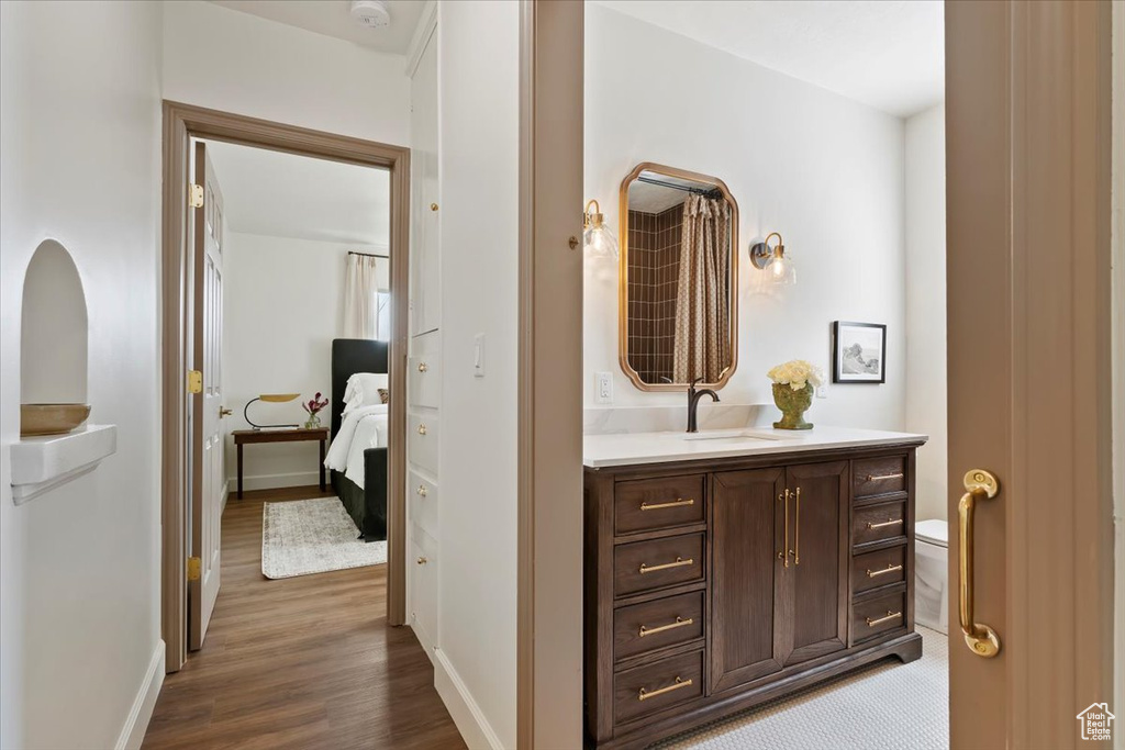Corridor with a sink, wood finished floors, and baseboards