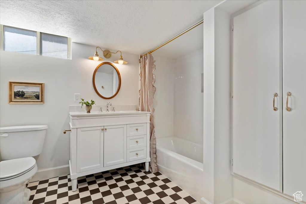 Bathroom featuring tile patterned floors, toilet, vanity, baseboards, and a textured ceiling