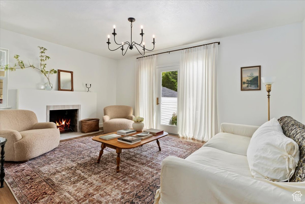 Living area with a chandelier, wood finished floors, and a tile fireplace