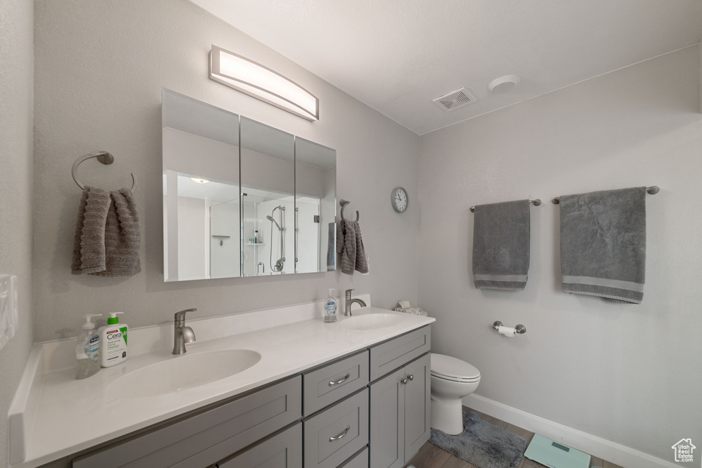 Full bathroom with toilet, visible vents, double vanity, and a sink