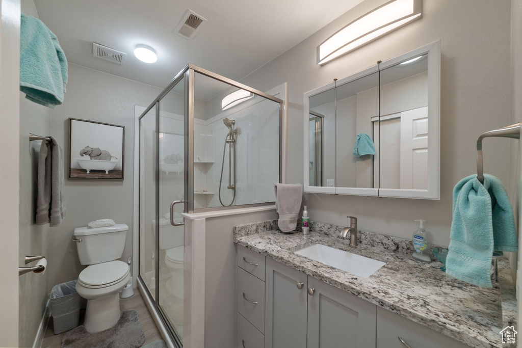 Full bathroom with toilet, visible vents, a shower stall, and vanity