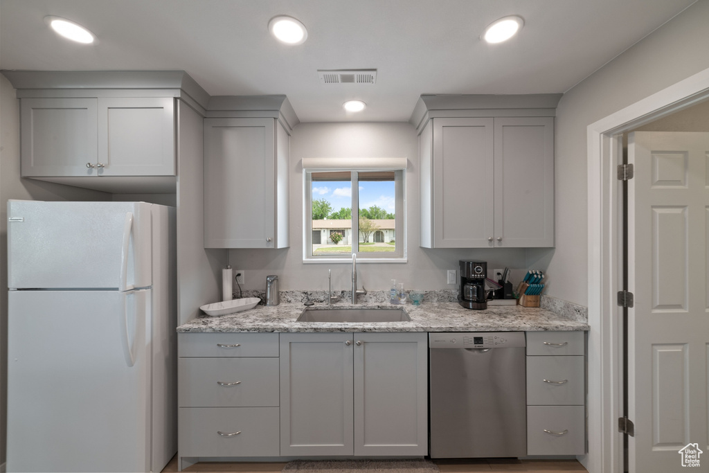 Kitchen featuring a sink, freestanding refrigerator, gray cabinets, stainless steel dishwasher, and visible vents