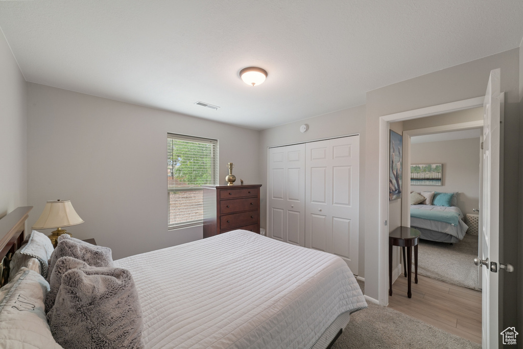 Bedroom featuring a closet, light wood-style floors, visible vents, and baseboards
