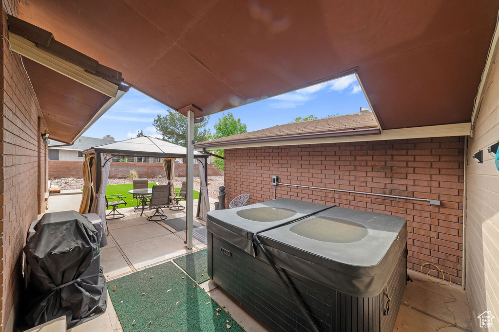 View of patio with a gazebo, area for grilling, outdoor dining space, and a hot tub