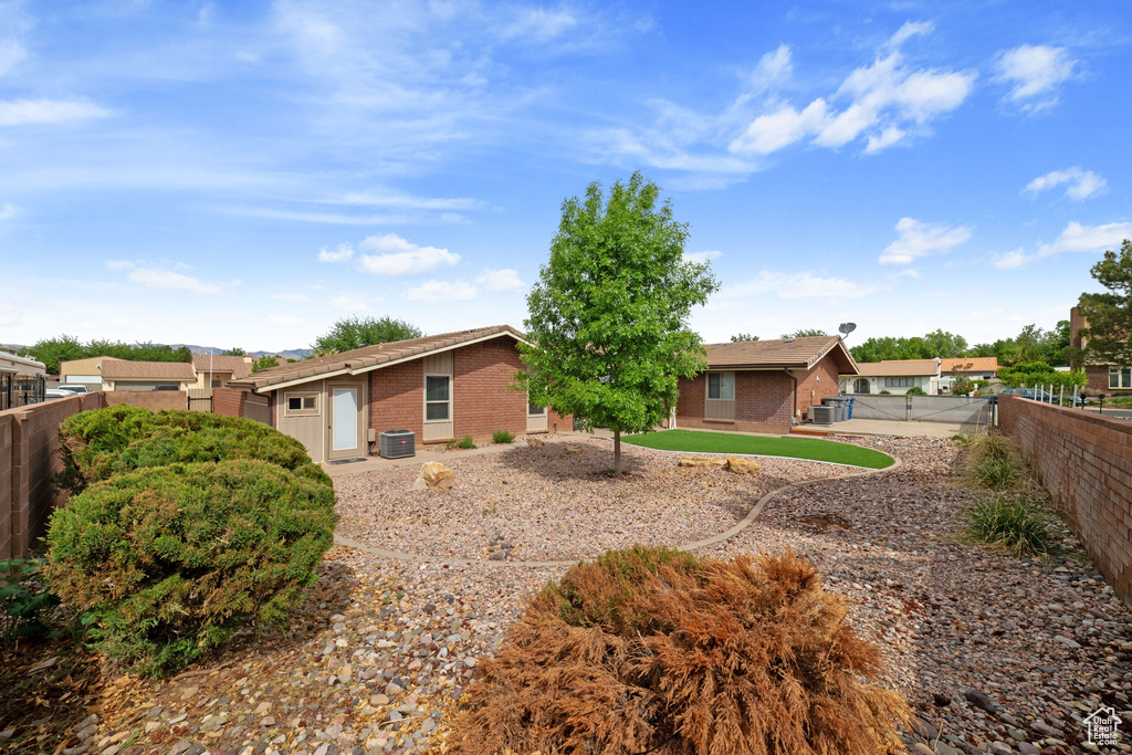 Exterior space with a fenced backyard, brick siding, and central AC